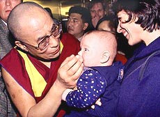 The Dalai Lama, exiled spiritual and political leader of Tibet, caresses a baby.
