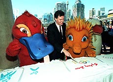Sydney 2000 Olympics minister Michael Knight cuts the World's longest Olympic cake measuring 16 metres in Sydney on Tuesday. He is assisted by the three Games' mascots, (from left) Syd the Platypus, Millie the Echidna and Olly the Kookaburra.
