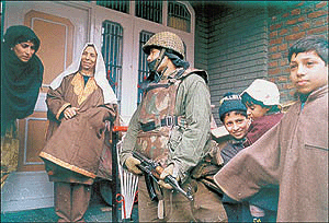 A security person seeks information from a woman in Srinagar.
