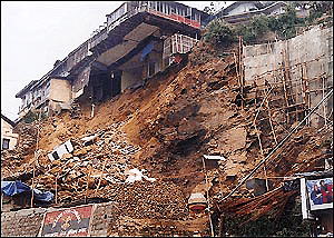 A portion of a house rests on the edge following a landslide at mid-night on Thursday. — photo by the writer