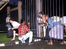 Gunmen direct mediapersons to keep low as they pass through the gates of Fiji's parliament building in Suva on Sunday.