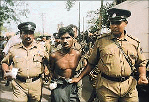 Two Sri Lankan policemen take a suspected colleague of the suicide bomber into custody.