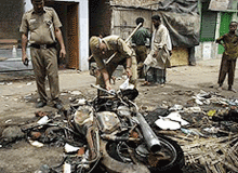 Policemen take out charred records from a burnt police vehicle in New Delhi on Saturday