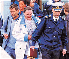A Russian marine officer walks with the parents of a sailer from Kursk submarine.