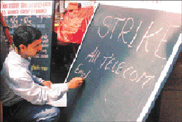 An employee of the Telecom Department writes on a board to announce a strike in Mumbai on Wednesday. Employees of the department began an indefinite strike on Wednesday to back the demand for job security. 