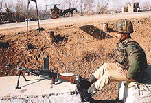 A paramilitary jawan mans his post as a "tonga" passes by at Sopore, 48 km north of Srinagar, on Tuesday.