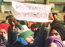 A Kashmiri Sikh youth holds a paper with the words We want migration during a protest at Mehjoor Nagar in Srinagar, on Monday.