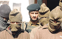 A BSF jawan stands guard behind a group of masked militants at a garrison in Srinagar on Friday.