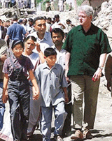 Former US President Bill Clinton, surrounded by earthquake survivors