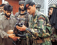 An Army officer receives a gun from Ghulam Nabi, a Kashmiri militant, during a surrender ceremony in a camp at a Magam village in Handwara, 74 km northwest of Srinagar, on Friday.