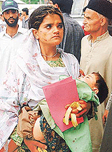 An unidentified wounded Kashmiri woman carries her injured child outside a hospital in Srinagar on Friday. 