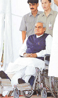 Prime Minister Atal Behari Vajpayee is wheeled out by security personnel for a news conference after he was discharged from hospital following a knee operation in Mumbai on Tuesday.  