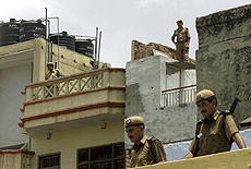 Policemen stand on rooftops surrounding the ancestral home of the grandfather of Pakistan President Pervez Musharraf in New Delhi on Thursday. Musharraf is due to visit the house during his trip to India this weekend. 