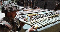 An Army jawan looking at the arms and ammunition recovered by troops.