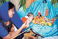 A young devotee bends over to have a glimpse of Lord Krishna in his cradle surrounded with offerings at Gaudia Math temple in Sector 20, Chandigarh, on the occasion of Janmashtami on Sunday.