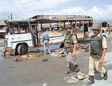 Securitymen inspect a bus that was damaged in an explosion killing one person and injuring nine others at the general bus stand, Batmaloo in Srinagar, on Monday.