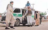 Several residents of the Afghan capital wait next to a minivan as they prepare to depart for Pakistan on Saturday.