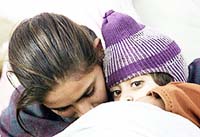 A Kashmiri girl holds her younger brother as they huddle against the cold at a refugee camp in Samba, about 40 km south of Jammu, early on Tuesday.