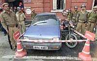 Policemen stand guard beside a seized vehicle
