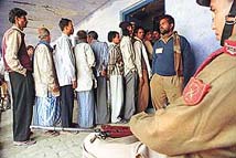 Security personnel stand guard as voters wait in line