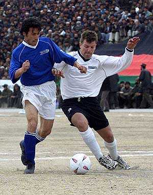 Kabul striker Sayed Tahir (L) is tackled by Pte Bowalter of the ISAF soccer team during Kabul's biggest sporting event in years 