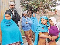 Wary relatives and neighbours of Krishan Singh, who reportedly died of plague, outside his residence at Kansal village, Ropar district, on Saturday.