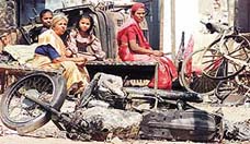 Residents of Ahmedabad sit outside their damaged house