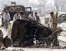A policeman stands besides a burnt vehicle