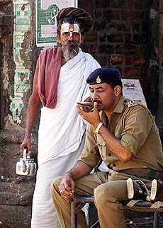 A sadhu offers tea to a policeman