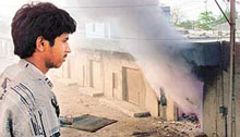A man watches smoke rise from a nearby shop burning on the outskirts of Ahmedabad on Monday.