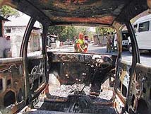 A woman walks past a burnt vehicle