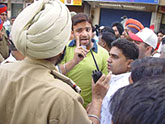 A policeman tries to defuse the tension between Congress and BJP supporters