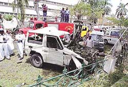 Police officers stand beside a damaged vehicle in front of the US consulate in Karachi after a bomb blast on Friday.