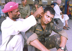 Homeward-bound, a jawan gets his ear cleaned from a roadside doctor while others wait for their turn before boarding a train for their destinations at Bathinda railway station on Thursday.