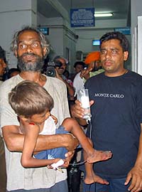 A slum-dweller holds his injured son while standing besides a family member in a hospital in Jammu on Saturday.