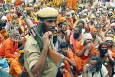 A policeman guards a group of sadhus on a pilgrimage in Jammu 