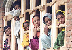 Villagers look out of a window to watch an election rally in Malangam in Jammu and Kashmir on Friday.
