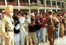 Policemen guard a long queue of voters at a polling station in Handwara