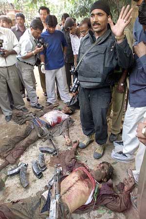 A commando gestures as he stands near the bodies of two militants