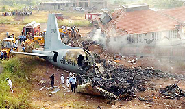 Military personnel walk around the debris of an Indian Naval plane that collided with another during a formation flight