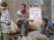 Workers rest in front of an election poster 