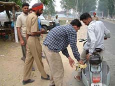 A wine contractors man checks a scooter in the presence of the police on the Rajasansi Airport road on Saturday