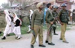 Kashmiri girls rush back to their homes as BSF jawans stand guard after an explosion at Sopore