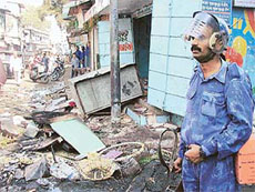 A jawan of the Rapid Action Force patrols near a burnt shop