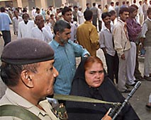 A paramilitary trooper stands guard near a crowd of voters in Ahmedabad during the Assembly elections in Gujarat 
