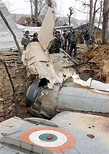 Air Force personnel and Army officials stand near the debris of a MIG-21