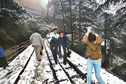 Tourists enjoy the seasons first snowfall near Shimla railway station on Tuesday.