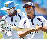 Sachin Tendulkar plays with his bat while Virender Sehwag puts on batting gloves for a practice session in Pretoria