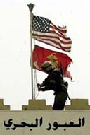 A Marine replaces the Iraqi flag with the Stars and Stripes and the flag of the Marine Corps