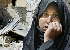 An Iraqi woman sits in front of a house destroyed during an air strike on the outskirts of Baghdad